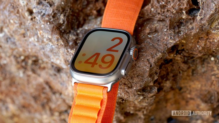 An Apple Watch Ultra rests on a rock wall displaying the X-Large watch face.