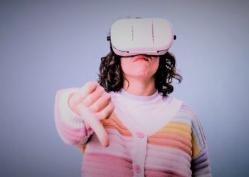 Woman showing thumb down while using VR virtual reality headset over an isolated background. Technology concept.